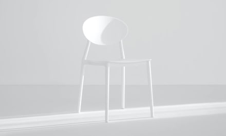 A white chair in a well lit pure white room.