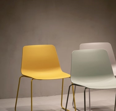 Three simple plastic chairs. One yellow, one gray, one pale green.