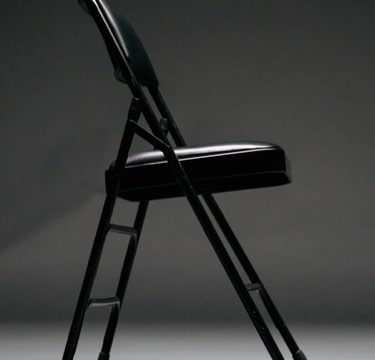 A black metal folding chair seen from the side.